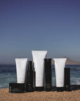 several Rejuva Fresh Brand Skin Care tubes and jars sit on the sand on the beach